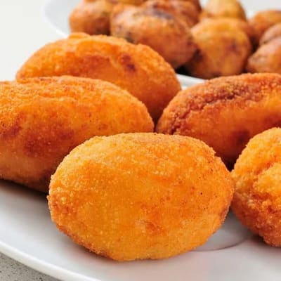 Croquetas recién fritas con el rebozado dorado, servidas en plato blanco
