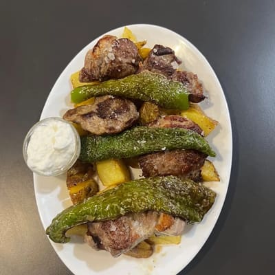 Medallones de carne a la plancha con pimientos verdes asados, patatas panadera y un cuenco de alioli