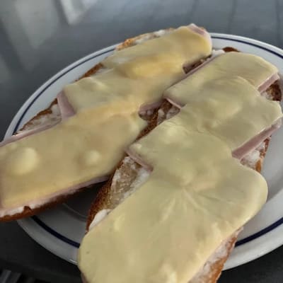 Dos rebanadas de pan tostado cubiertas de fiambre y queso fundido